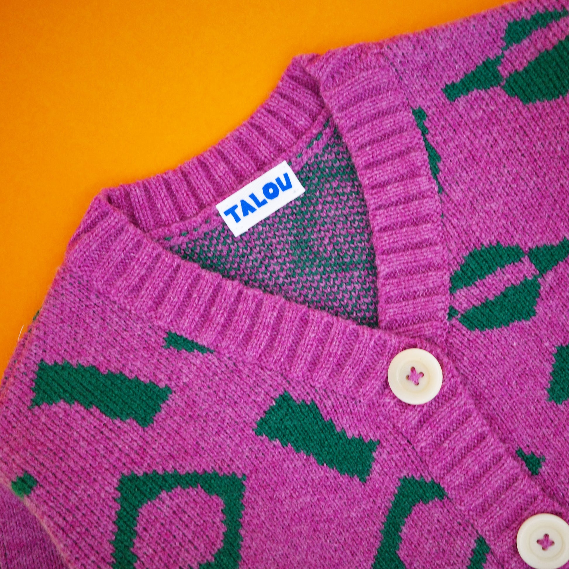 Neckline and buttons of pink and green wool children's cardigan.